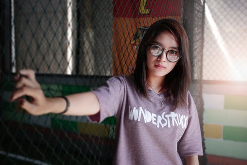 Woman Leaning on Black Cyclone Wire