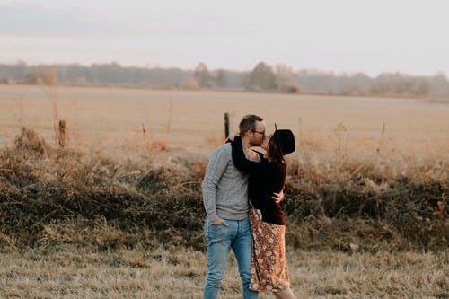 Man and Woman Kissing on Brown Grass Field