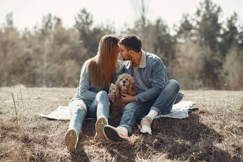 Loving couple having rest with dog on lawn
