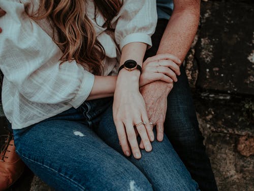 Woman In Blue Denim Jeans And White Top Sitting On Man's Lap